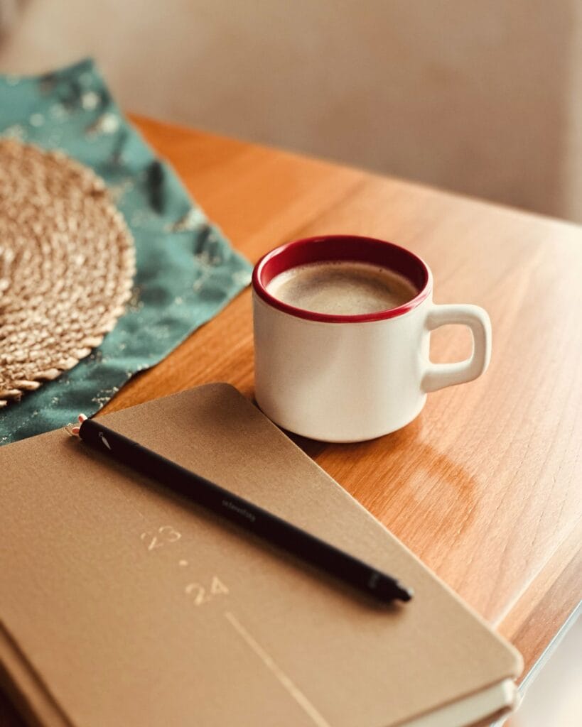 Coffee mug and planner on a wooden table in warm light